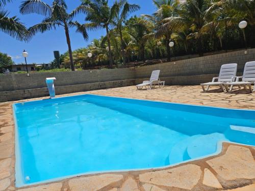 een blauw zwembad met 2 stoelen en palmbomen bij Refúgio GRUPOS com piscina, churrasqueiras 38 min Águas Claras Brasília in Brasilia