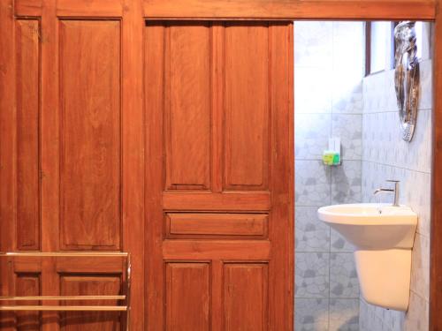 a bathroom with a wooden door and a sink at Pendhapa Art Space - PAS Limasan Homestay in Yogyakarta