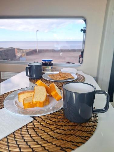 a table with a plate of bread and a cup of coffee at Camper La Palma fianza 600eu in Santa Cruz de la Palma
