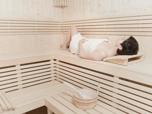 a woman laying on a bed in a sauna at Hotel Na Skarpie - Charzykowy in Charzykowy
