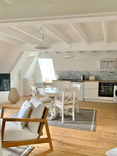 un salon avec une table et des chaises blanches dans l'établissement Charmant F2 Atypique Coutances centre, à Coutances