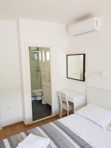 a white bedroom with a desk and a mirror at Apartments Vala 2 in Grebaštica