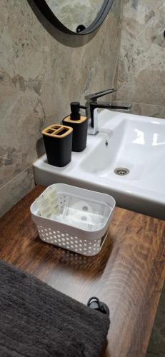 a bathroom sink with a basket on a wooden floor at Lux GUEST HOUSЕ МUKACHEVO in Mukacheve