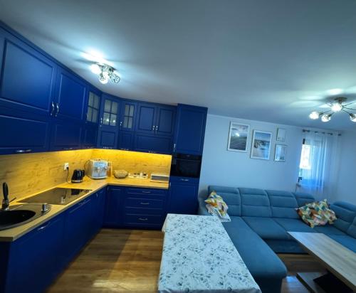 Una cocina con gabinetes azules y un sofá azul. en Apartament Błękitny, en Krynica Morska