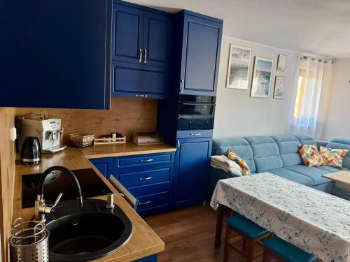 Una cocina con gabinetes azules y un fregadero. en Apartament Błękitny, en Krynica Morska