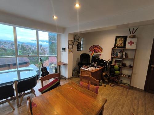 a living room with a table and chairs and a large window at linda house cusco in Cusco