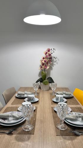 a wooden table with plates and wine glasses on it at Apartamento no Iloa Residence - Com Enxoval Completo in Barra de São Miguel