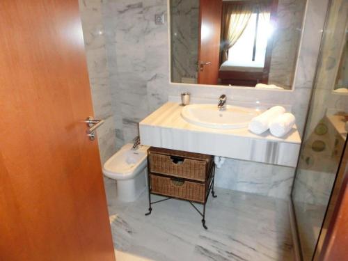 uma casa de banho com um lavatório, um WC e um espelho. em Apartamentos Parque Botanico em Estepona