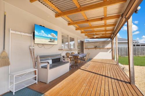 a covered deck with a television and a table at Armstrong Cottage in Paynesville