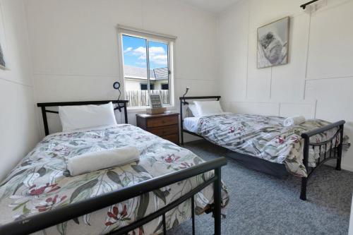 zwei Betten in einem Zimmer mit Fenster in der Unterkunft Armstrong Cottage in Paynesville