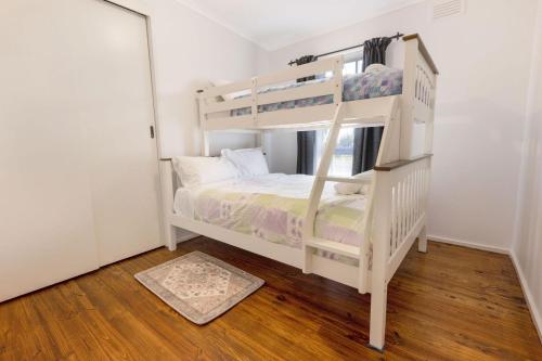 a white bunk bed in a white room with a ladder at Shelby Cottage in Paynesville