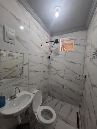 a white bathroom with a toilet and a sink at Pousada uberaba in Uberaba