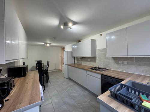 a kitchen with white cabinets and a wooden counter top at IcandoWorld Reading House in Earley