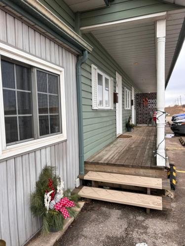 a green house with a wooden porch with flowers on it at Smokehouse Suites and Stay in Guelph