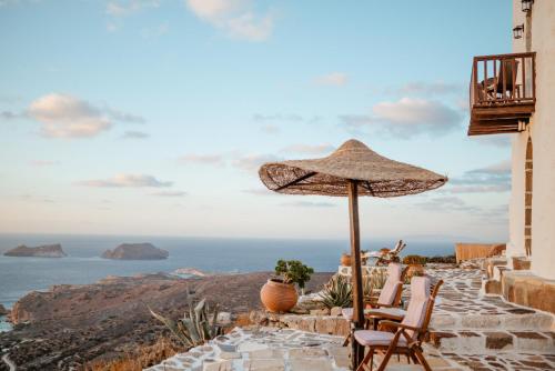 a patio with chairs and an umbrella and the ocean at Castrum Traditional Sunset Suites in Plaka Milou
