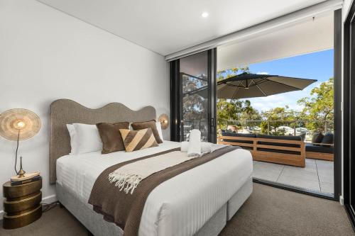 a bedroom with a bed and a balcony with an umbrella at Oceanview Penthouse by Experience Jervis Bay in Huskisson