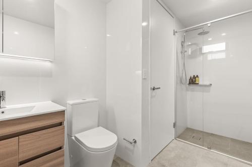 a white bathroom with a toilet and a shower at Oceanview Penthouse by Experience Jervis Bay in Huskisson