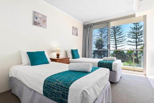 two beds in a room with a window at Northwind Beachfront Apartments in Mooloolaba