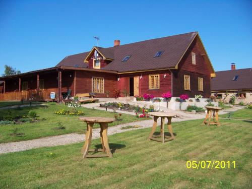 two picnic tables in front of a house at Lauku Mājas Ēmužas in Dārte