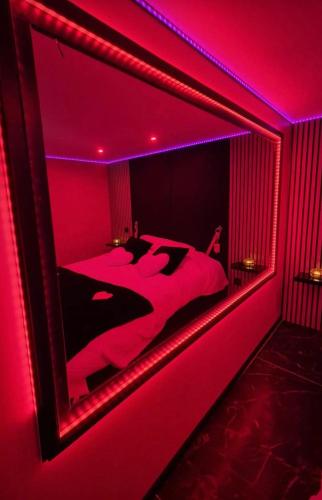 Cette chambre rouge comprend un lit avec un grand miroir. dans l'établissement Love room, à Maureilhan-et-Raméjan