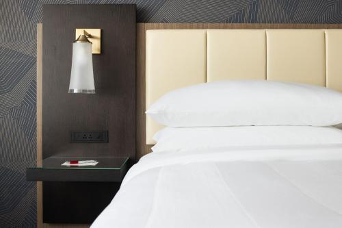 a bedroom with a white bed and a side table at Marriott Bloomington Normal Hotel and Conference Center in Bloomington