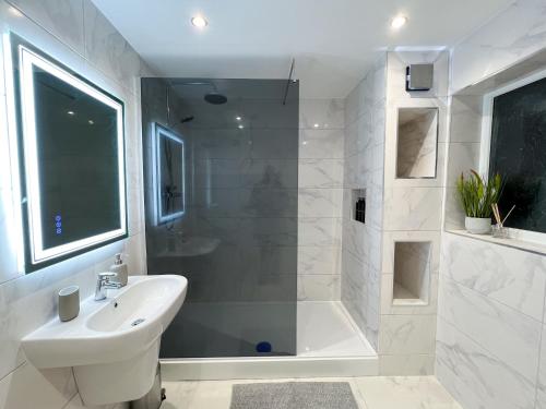 a white bathroom with a sink and a shower at Stylish 2 Bedroom Flat City Centre - Free Parking in Cardiff