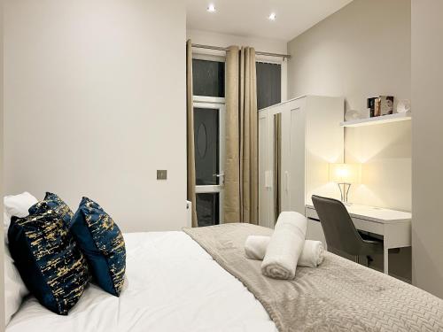 a bedroom with a white bed with pillows and a desk at Stylish 2 Bedroom Flat City Centre - Free Parking in Cardiff