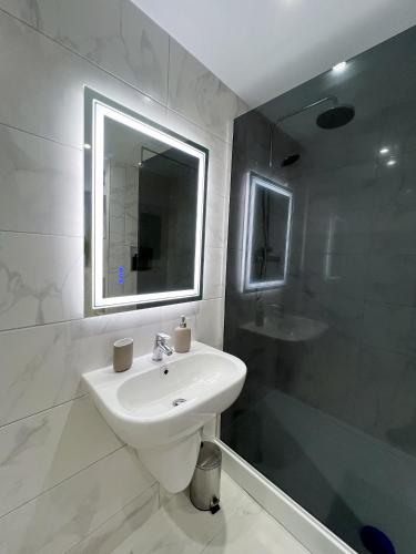 a white bathroom with a sink and a shower at Stylish 2 Bedroom Flat City Centre - Free Parking in Cardiff