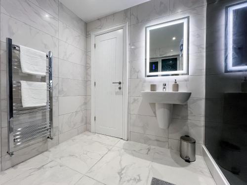 a white bathroom with a sink and a mirror at Stylish 2 Bedroom Flat City Centre - Free Parking in Cardiff