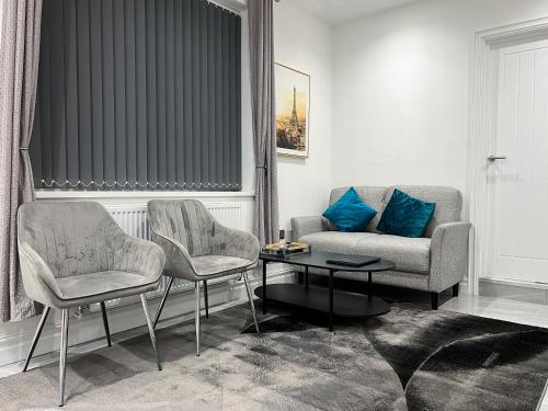 a living room with two chairs and a couch and a table at Stylish 2 Bedroom Flat City Centre - Free Parking in Cardiff