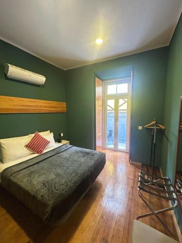 a bedroom with a bed with green walls and a window at Sao Jorge Apartments & Suites in Lisbon