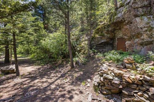 a path in a forest with a stone wall and trees at Boulder Luxury Getaway 7 acres River & Pond in Boulder