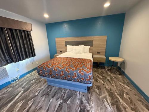 a bedroom with a bed and a blue wall at Travel Inn Motel in Anaheim