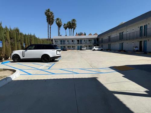 a white car parked in a parking lot next to a building at Travel Inn Motel in Anaheim