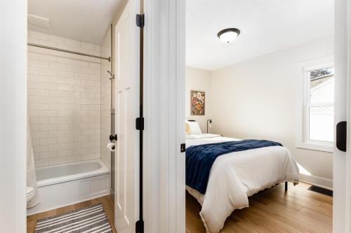 a white bedroom with a bed and a bath tub at End Zone Escape - 2BR house 1 mile to ND Stadium! in South Bend