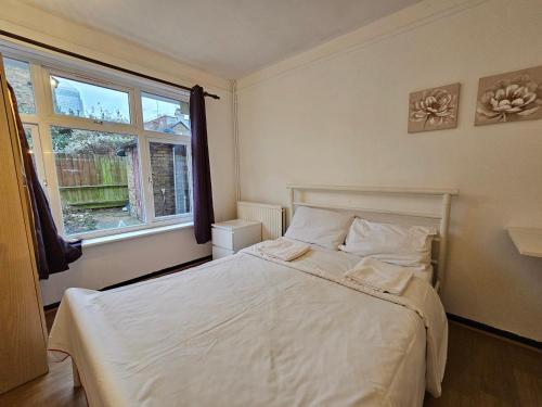 a bedroom with a white bed and a window at Rooms Near Canary wharf in London