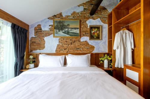 a bedroom with a white bed and a brick wall at Twelve 8 Boutique House in Phuket Town