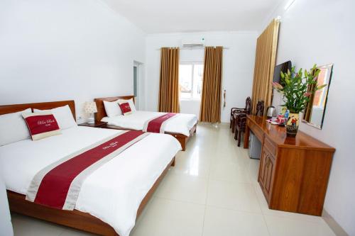 a hotel room with two beds and a desk at Hòa Bình Tam Đảo Hotel in Tam Ðảo