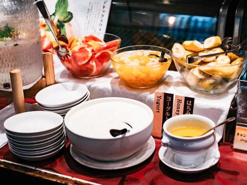 a table with plates and cups and bowls of food at Hotel Resol Trinity Kanazawa in Kanazawa