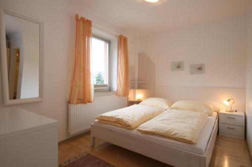 a white bedroom with a bed and a window at Appartements Schwaiger by Schladming-Appartements in Schladming