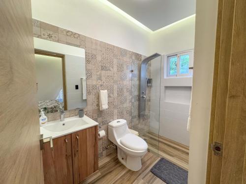 a bathroom with a toilet and a sink and a mirror at Villa Koi con Piscina privada climatizada in Punta Cana
