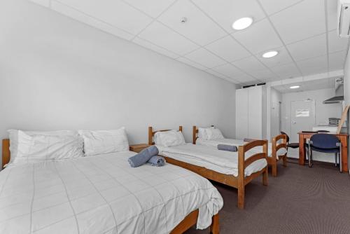 a room with two beds and a table and chairs at Onehunga Suites in Auckland