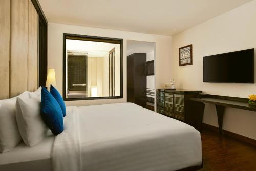 a bedroom with a white bed and a television at Mövenpick Hotel Sukhumvit 15 Bangkok in Bangkok