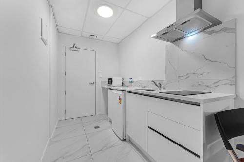 a white kitchen with a sink and a shower at Onehunga Suites in Auckland