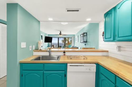 a kitchen with blue cabinets and a sink at Commodore 202 - Thomas Drive Paradise in Panama City Beach