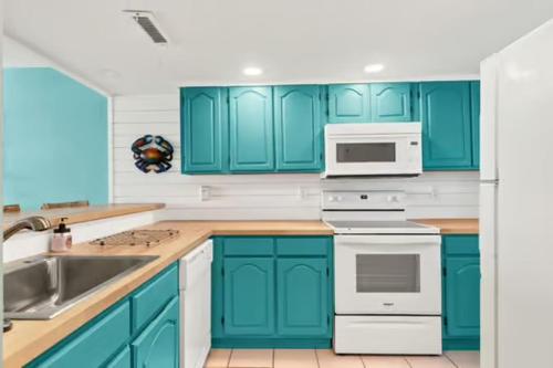 a blue kitchen with white appliances and blue cabinets at Commodore 202 - Thomas Drive Paradise in Panama City Beach