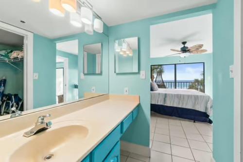 a bathroom with a sink and a mirror and a bedroom at Commodore 202 - Thomas Drive Paradise in Panama City Beach