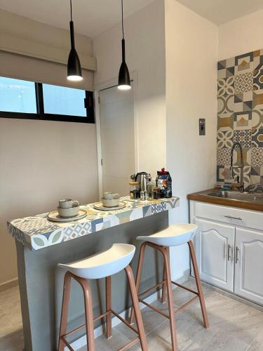 a kitchen with two bar stools and a counter top at Estudio - Roof Garden en Tula in Tula de Allende