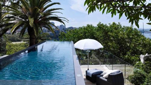a swimming pool with an umbrella and some trees at Little Darling in Sydney