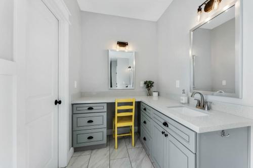 a white bathroom with a sink and a yellow stool at Large Flagstaff Home Near Violas with Hot Tub in Flagstaff